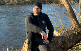 Dennis mit der Thermowave ReNew Merino Jacket auf einem umgestürzten Baum.
